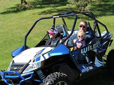 Current owners, Brian and Becca Gellner, ride with their daughter in a blue and white UTV.