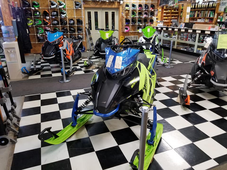 Bright snowmobiles line the dealership's showroom floor.
