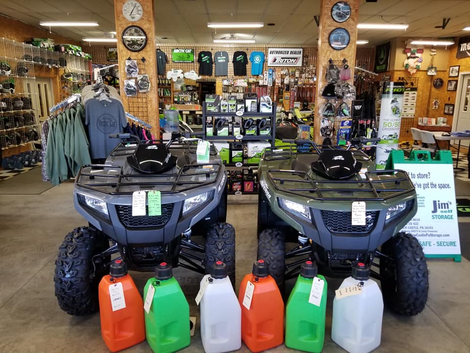 The dealership showroom floor features a red and white UTV and a green and white snowmobile.